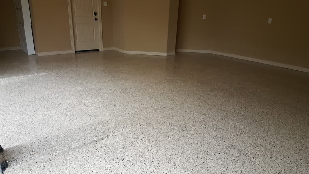 Newly polished concrete floor in a spacious, empty room with beige walls.