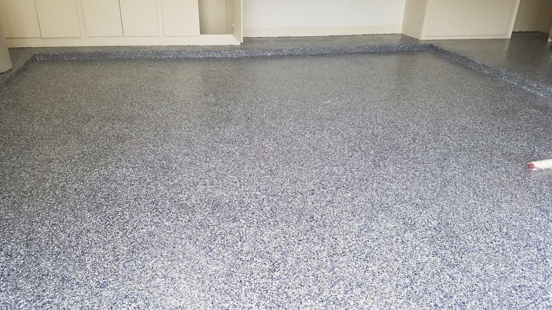 Epoxy-coated floor with blue flakes in a spacious room ready for furnishing.
