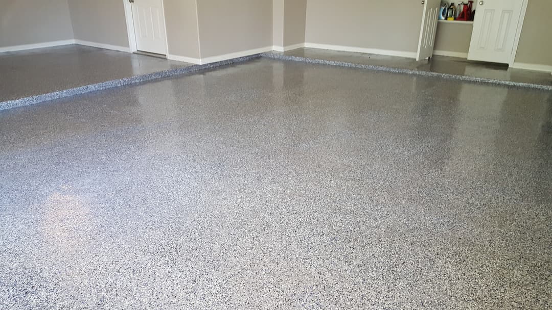 Polished epoxy floor in a modern garage with gray and blue flakes. Clean and smooth surface.