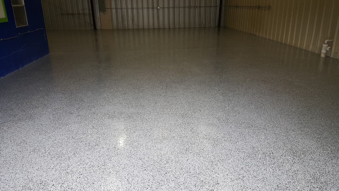 Shiny epoxy flooring in a spacious industrial garage with blue accent wall.