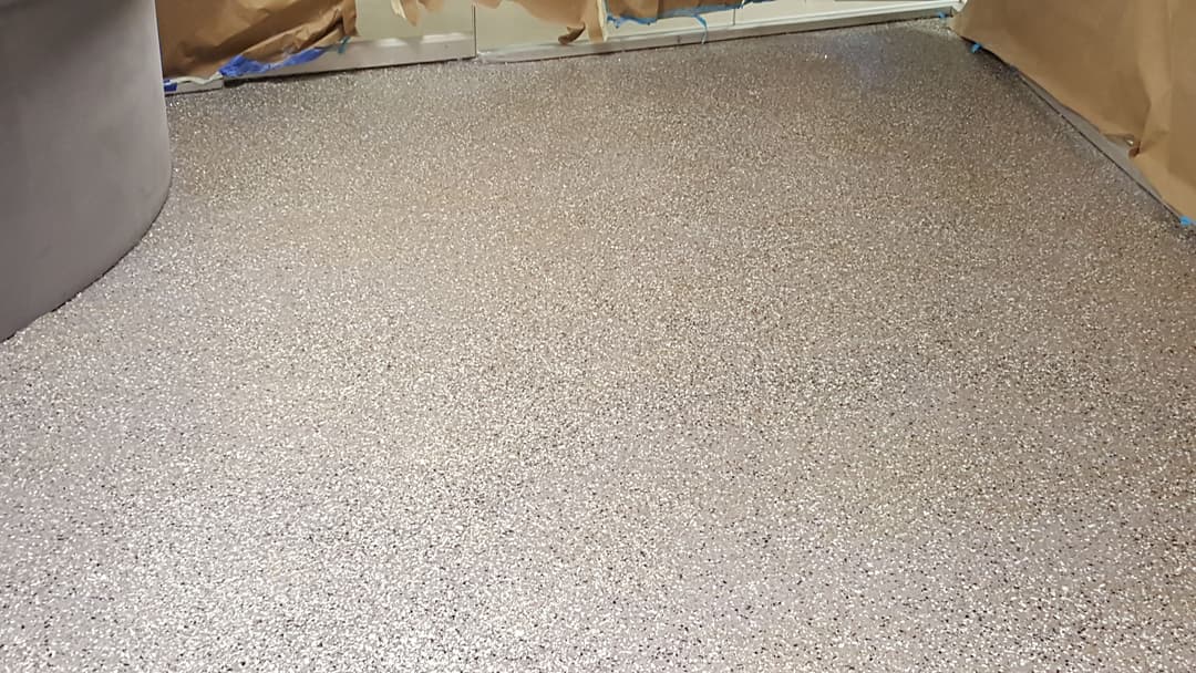 Newly installed epoxy floor with shiny, speckled finish in a partially renovated space.