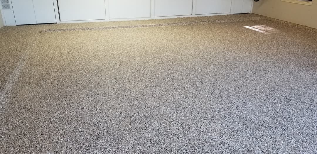 Epoxy coated floor in a garage with a smooth, speckled finish and natural light.