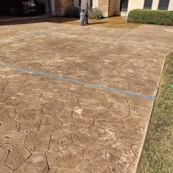 Man working on a stamped concrete driveway installation with hexagonal patterns.