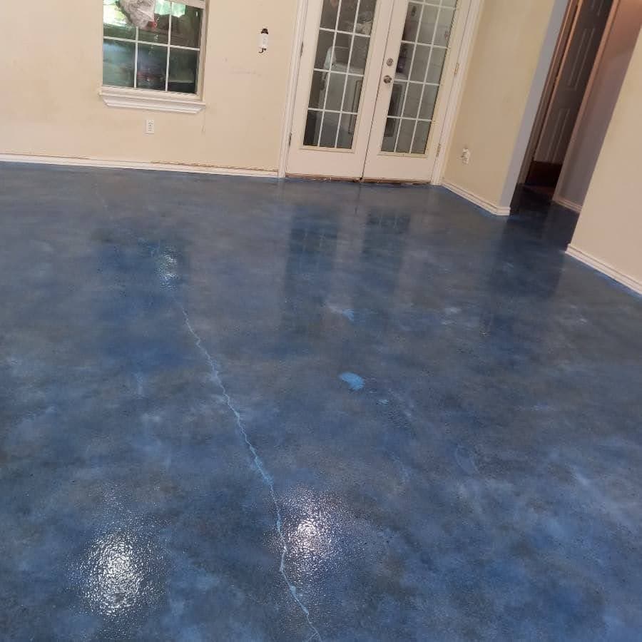 Shiny blue epoxy floor in a living room with glass doors and beige walls.
