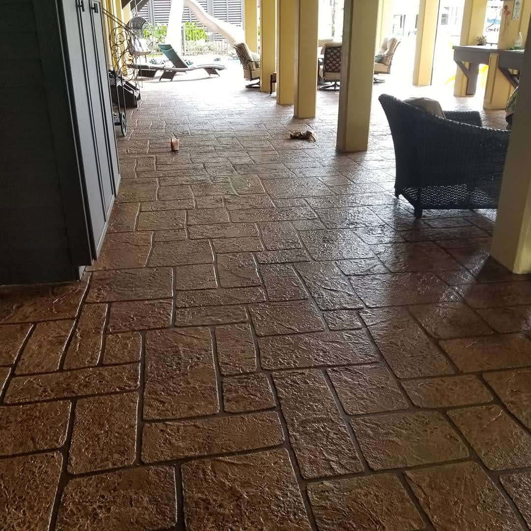 Textured concrete patio with seating area and ample natural light, enhancing outdoor space appeal.