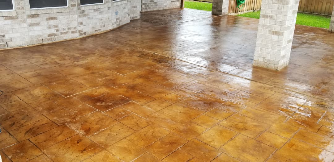 Stained concrete patio with a glossy finish and a green backyard view.