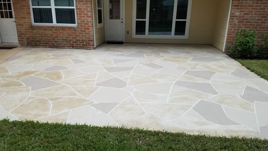 Textured patio design with light-colored stone tiles and green grass, enhancing outdoor space.