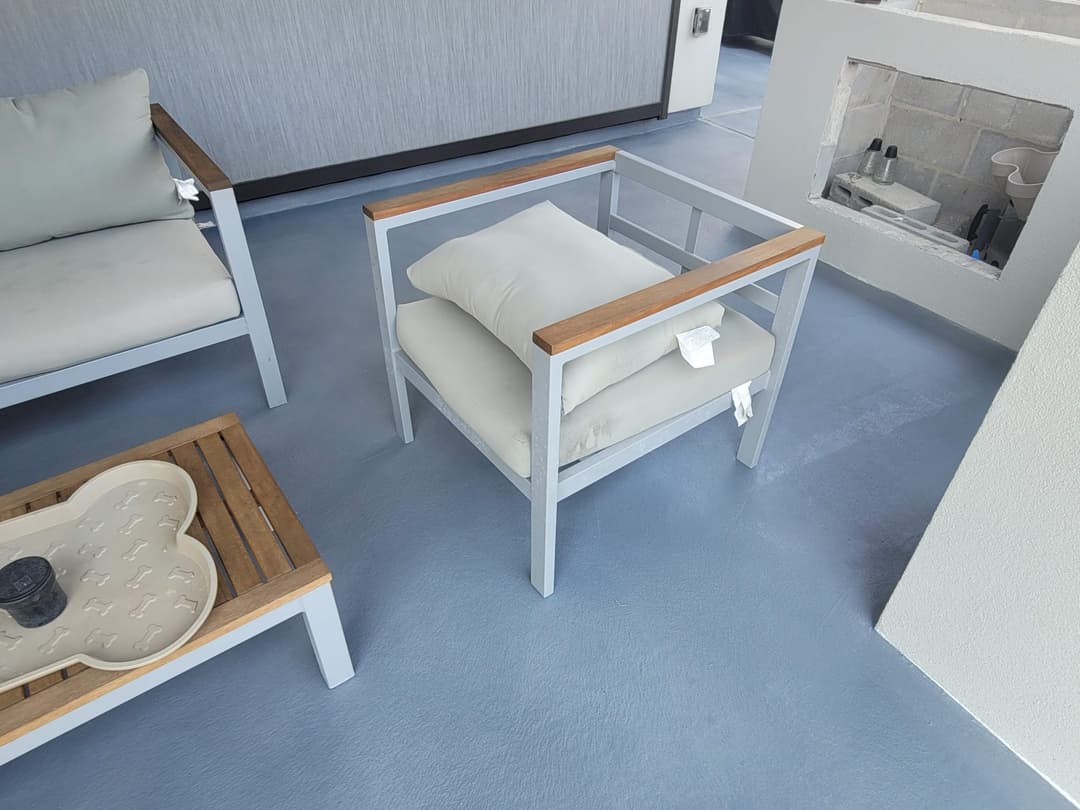 Modern outdoor lounge area with grey floor, minimalist seating, and stylish wood accents.