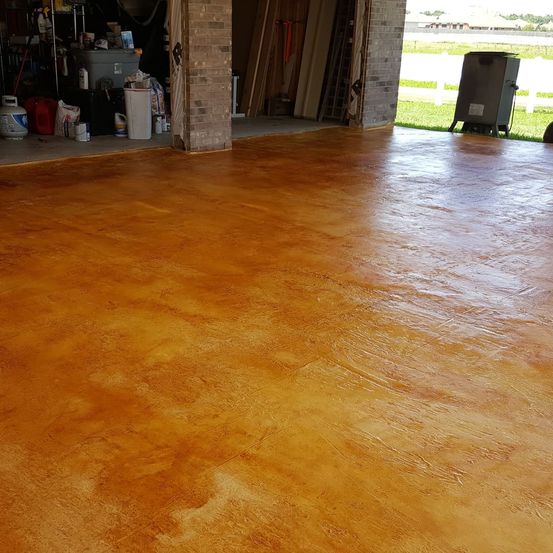 Polished orange epoxy garage floor with tools and equipment visible in the background.