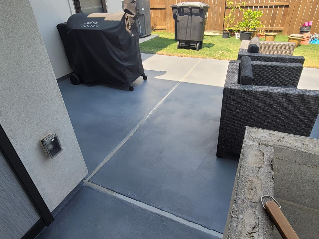 Outdoor patio featuring a gray concrete surface, barbecue grill, and wicker furniture.