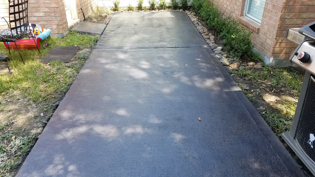 Freshly poured concrete walkway with sun-dappled shadows and landscaped edges.
