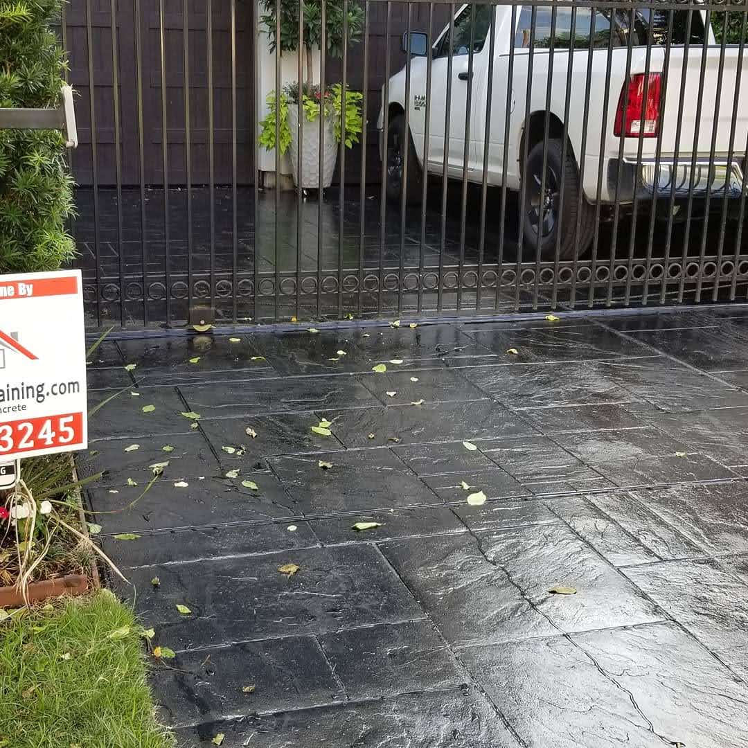 White pickup truck parked behind a black gated entrance with a decorative planter.