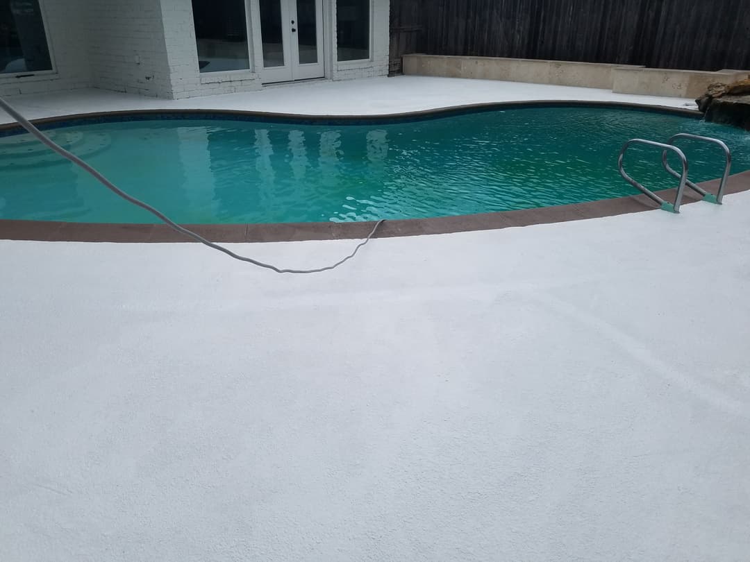 Residential swimming pool surrounded by white deck and wooden fencing. Clean water visible.