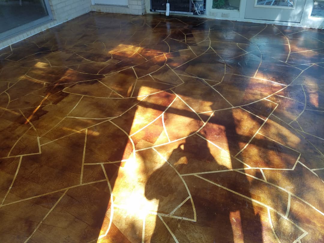 Textured brown and gold stained concrete floor with geometric patterns and playful shadows.