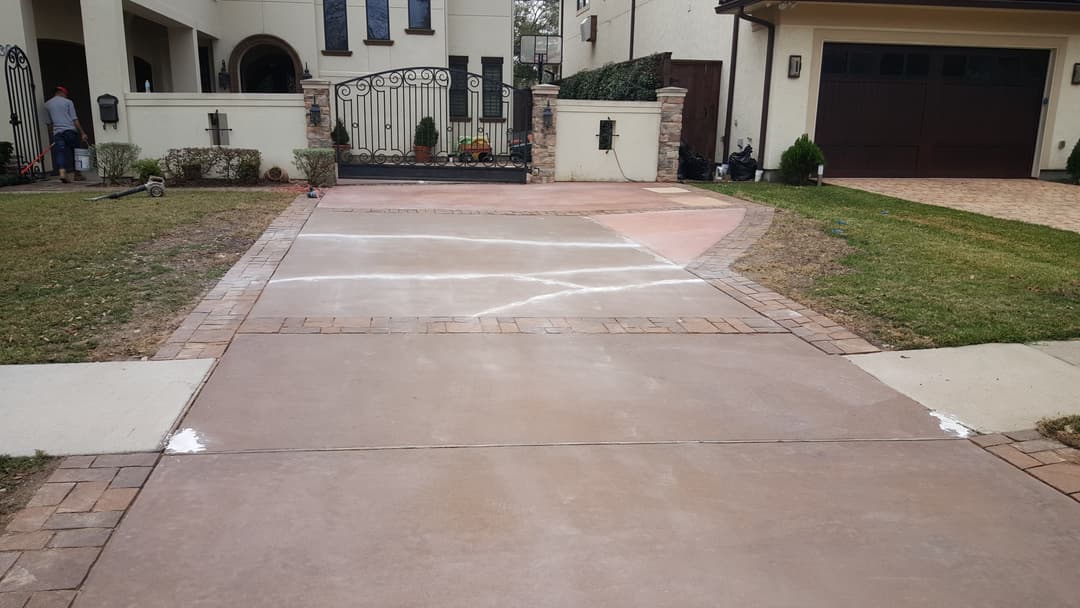 Freshly completed concrete driveway with decorative pavers, surrounded by well-maintained landscaping.