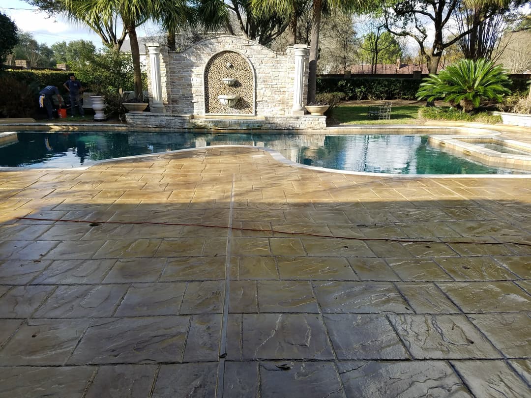 Luxury backyard with pool, elegant stone wall fountain, and tropical landscaping.