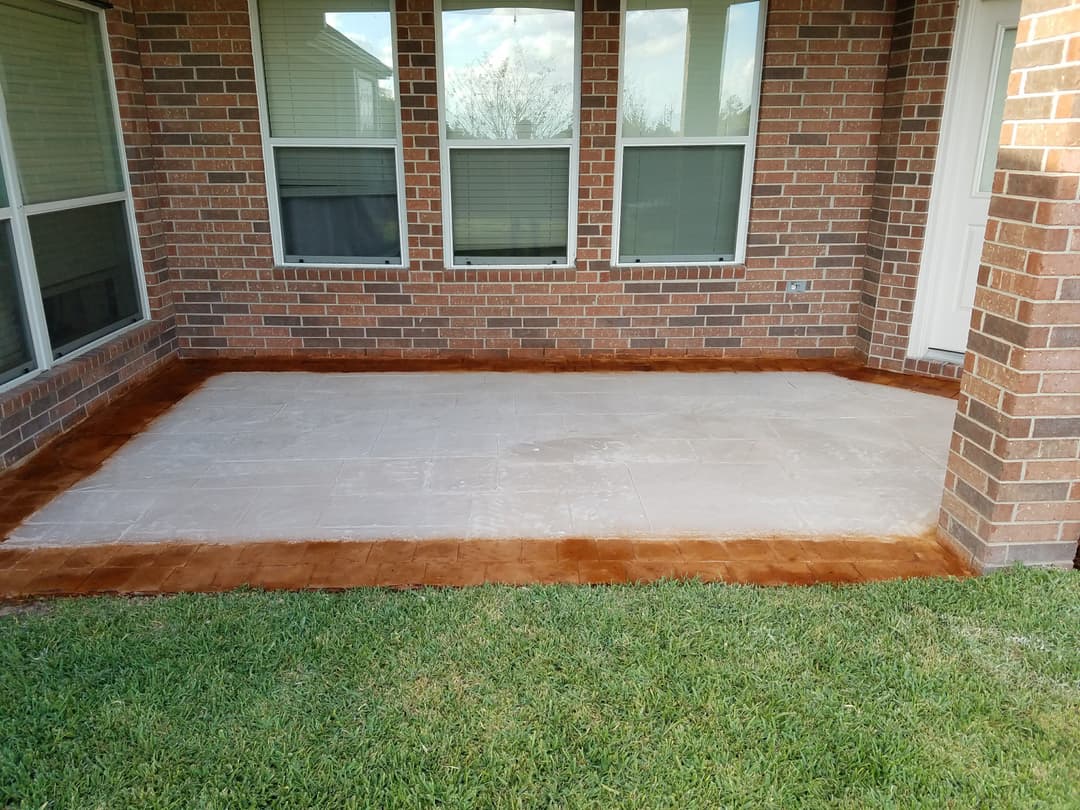 Patio with stained concrete floor, surrounded by brick walls and large windows.