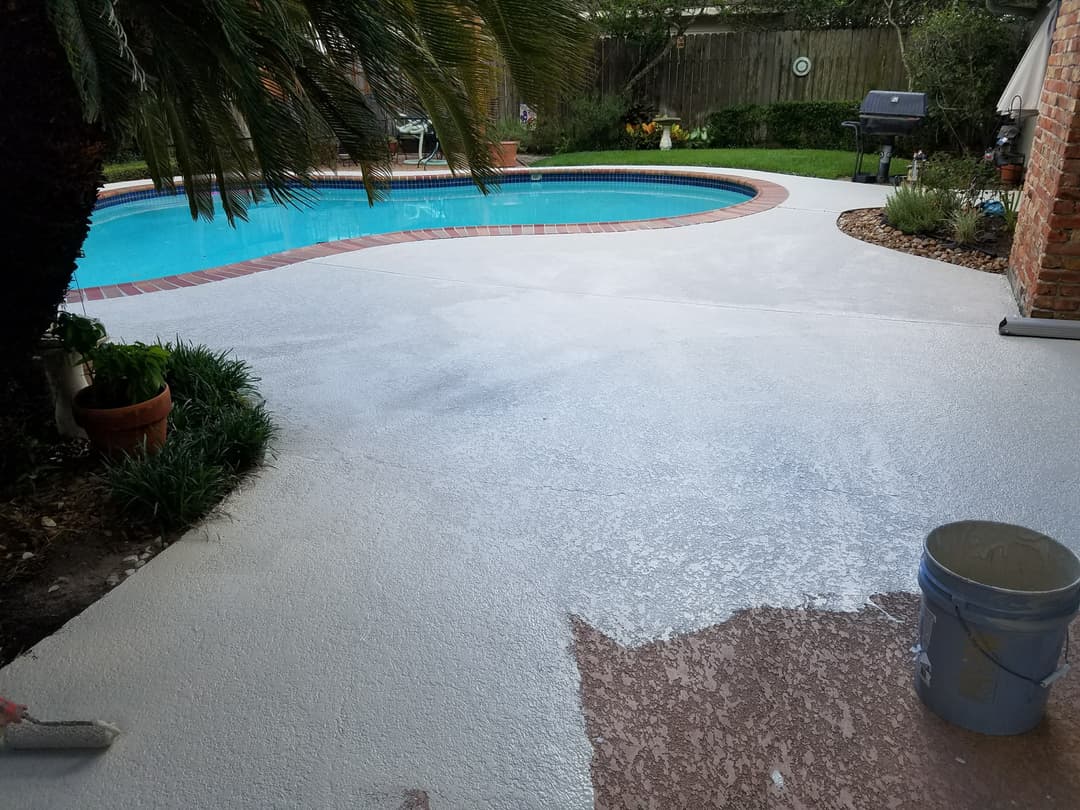 Poolside patio with fresh concrete coating, surrounded by greenery and decorative accents.