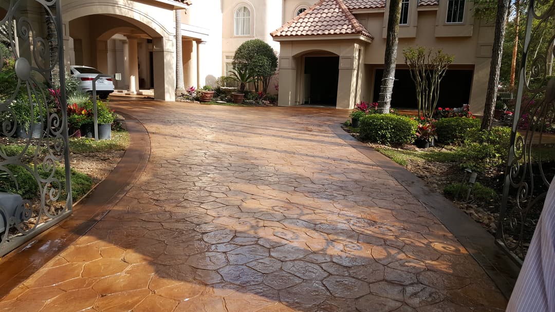 Decorative stamped concrete driveway with colorful landscaping and home entrance.