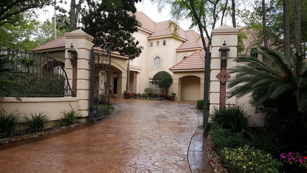 Elegant luxury home entrance with lush landscaping and a decorative driveway.