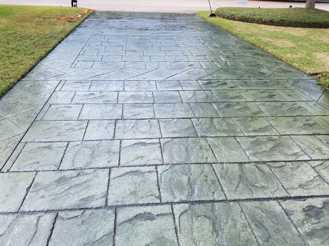 Stamped concrete pathway with a textured stone finish, surrounded by neatly trimmed grass.