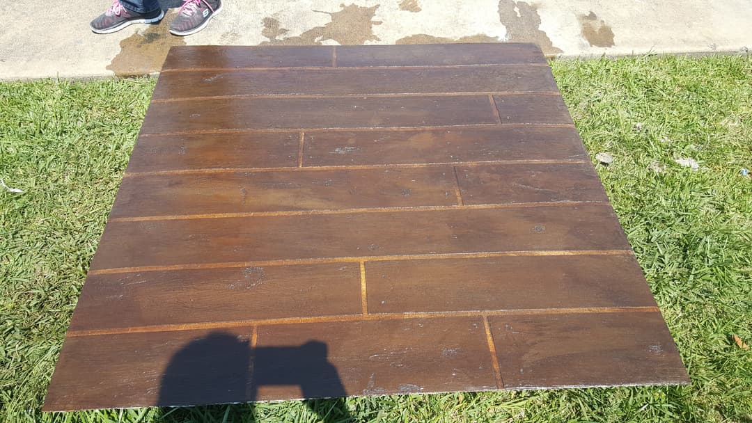 Wooden panel on grass, showing a polished surface and sunlight reflections.