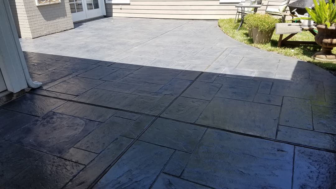 Stylish stamped concrete patio with a smooth finish and curved edges, surrounded by greenery.