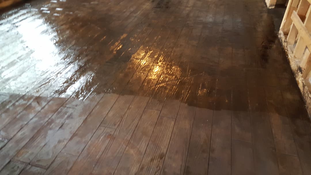 Shiny hardwood floor with wet sheen, reflecting light in a spacious interior setting.