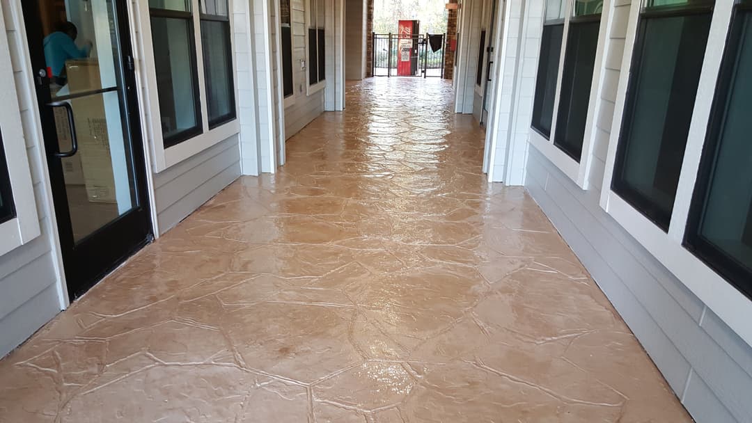 Decorative stamped concrete hallway with a smooth finish and sunlight filtering through windows.