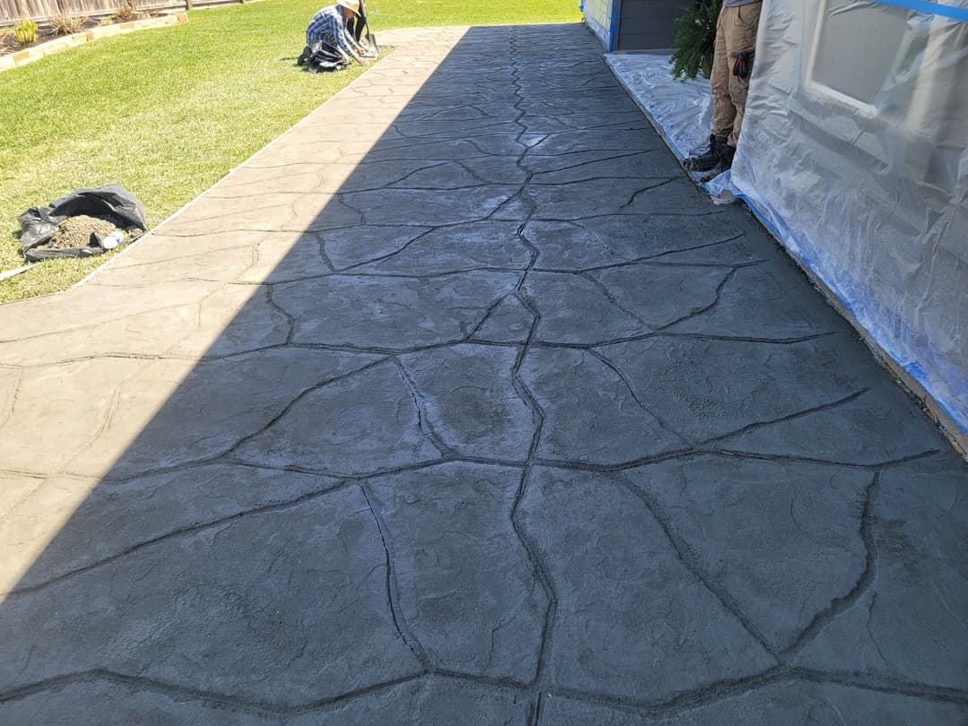 Decorative stamped concrete pathway with a textured stone pattern in a residential yard.