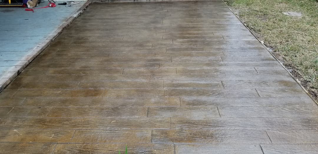 Textured concrete patio with a wood-like finish, freshly poured and drying on a sunny day.