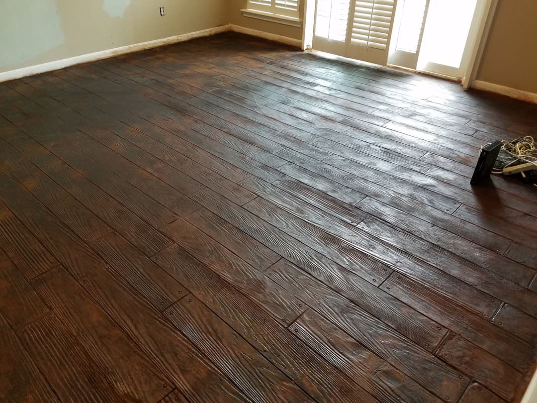 Newly installed dark wooden flooring in a bright room with sunlight streaming through windows.