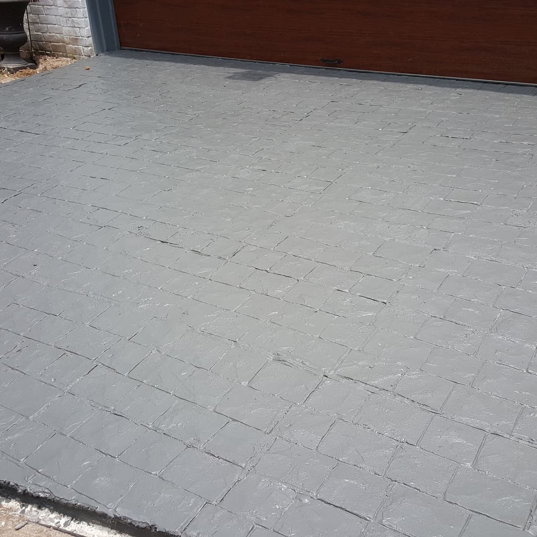 Textured gray stamped concrete surface in front of a garage door, clean and well-finished.