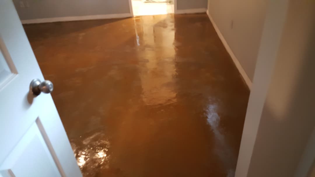 Newly polished orange concrete floor in a well-lit room with an open door.