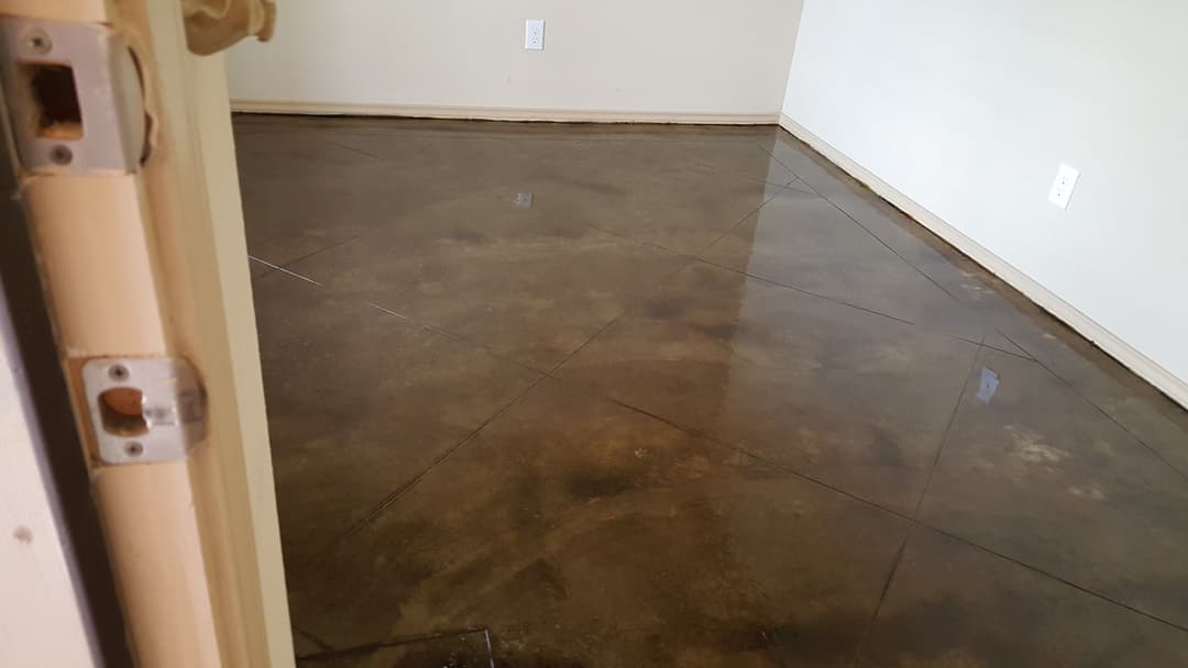 Concrete polished floor in an empty room with geometric lines and natural light.