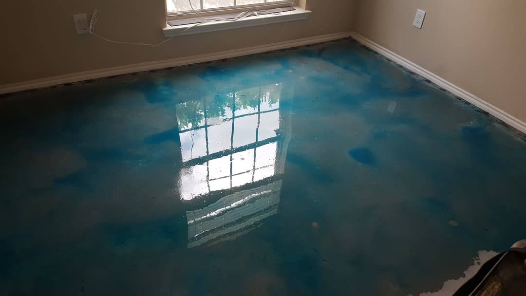 Blue epoxy floor with reflective surface in a well-lit room.