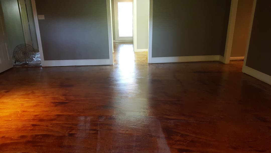 Interior view of a home showcasing a polished wooden floor and gray walls.
