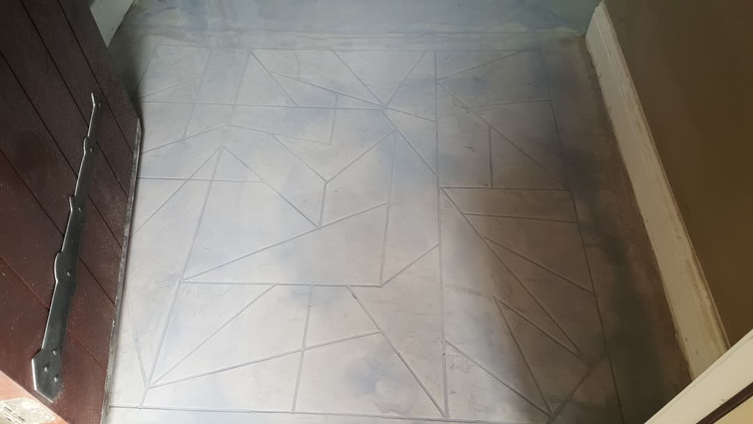 Textured concrete floor with geometric patterns in a dimly lit room.