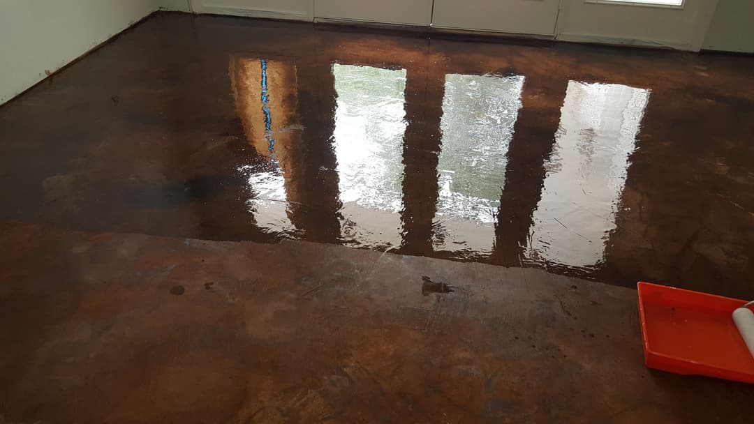 Glossy stained concrete floor drying with reflections of windows and natural light.