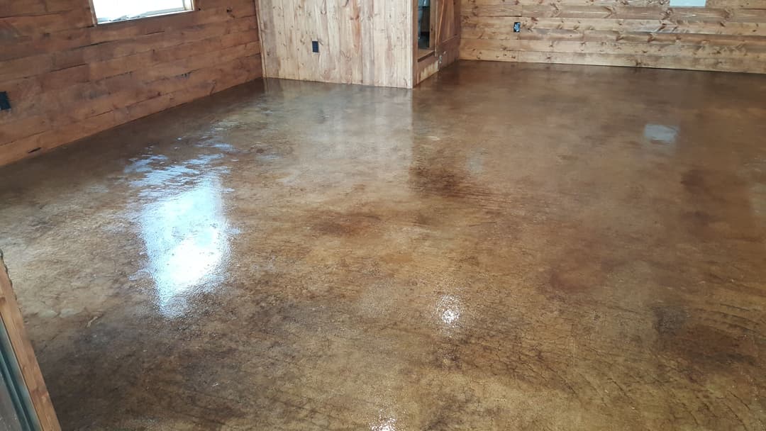 Interior view of a polished concrete floor in a wooden cabin, showcasing a warm brown finish.