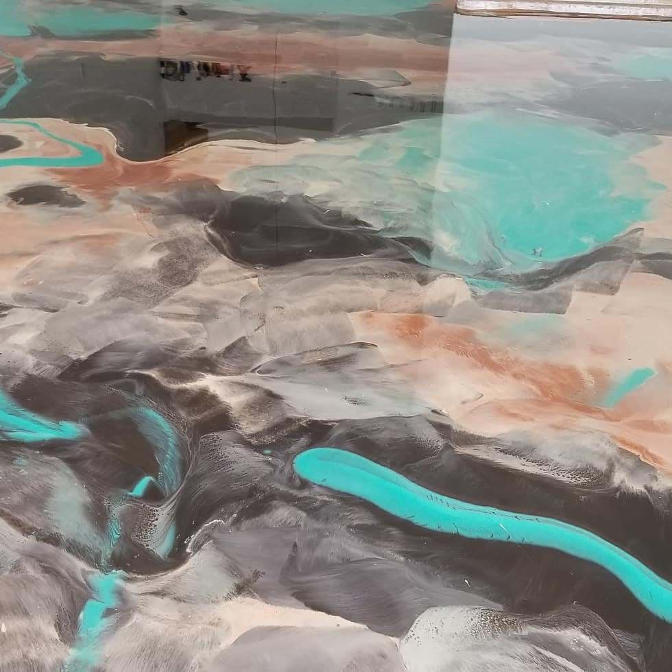 Abstract resin art featuring swirling patterns of turquoise, black, and earthy tones.
