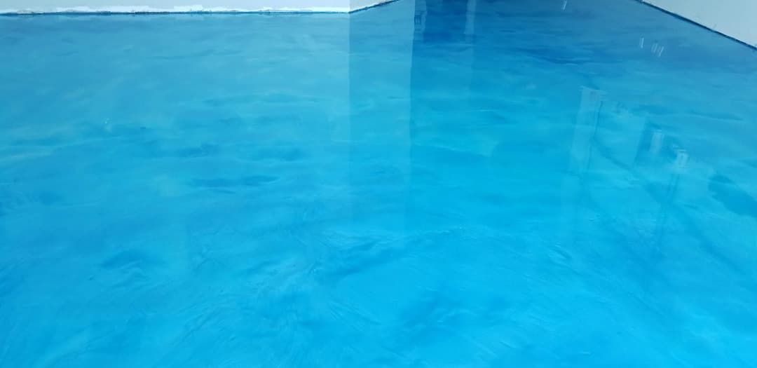Vibrant blue epoxy floor in a modern interior space with reflections.
