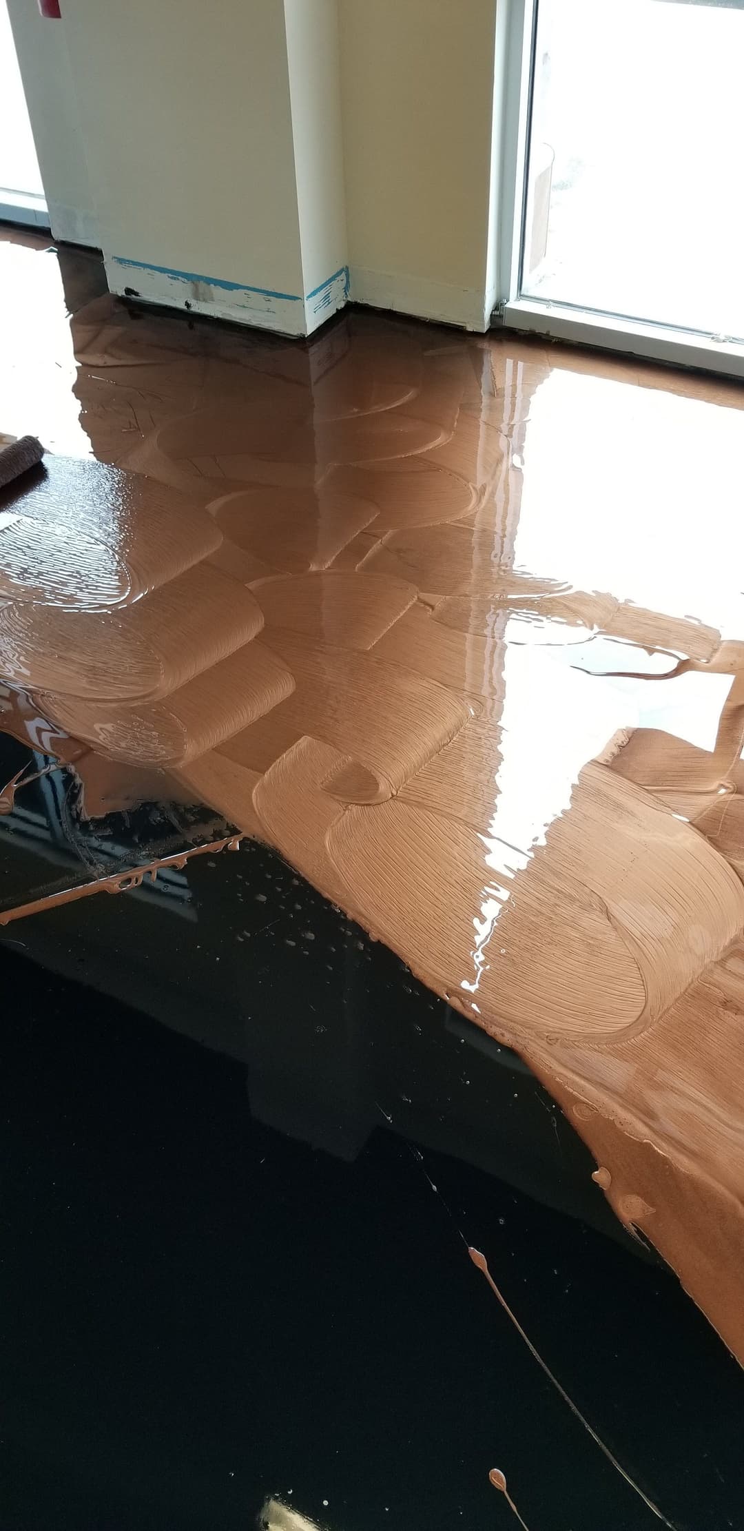 Freshly poured epoxy resin floor with a glossy finish in a sunlit interior space.