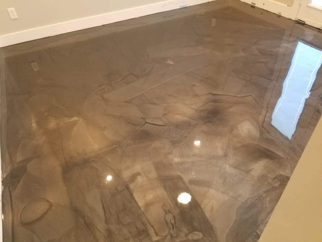 Polished gray epoxy floor reflecting light in contemporary interior space.