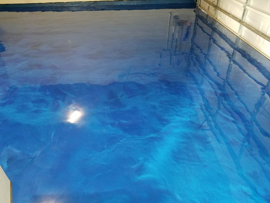 Blue glossy epoxy floor coating in a garage, reflecting light and creating a vibrant surface.