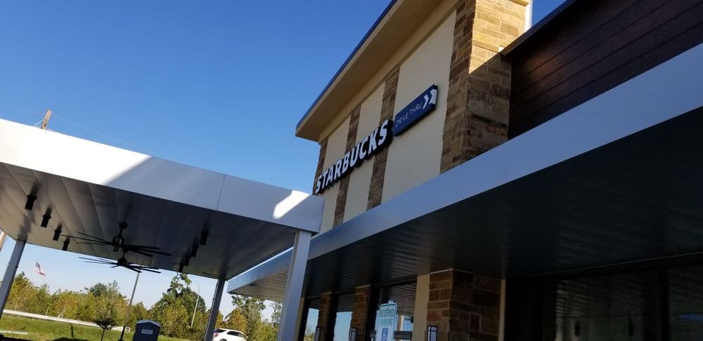 Starbucks storefront with sign, blue sky, and modern architectural design.