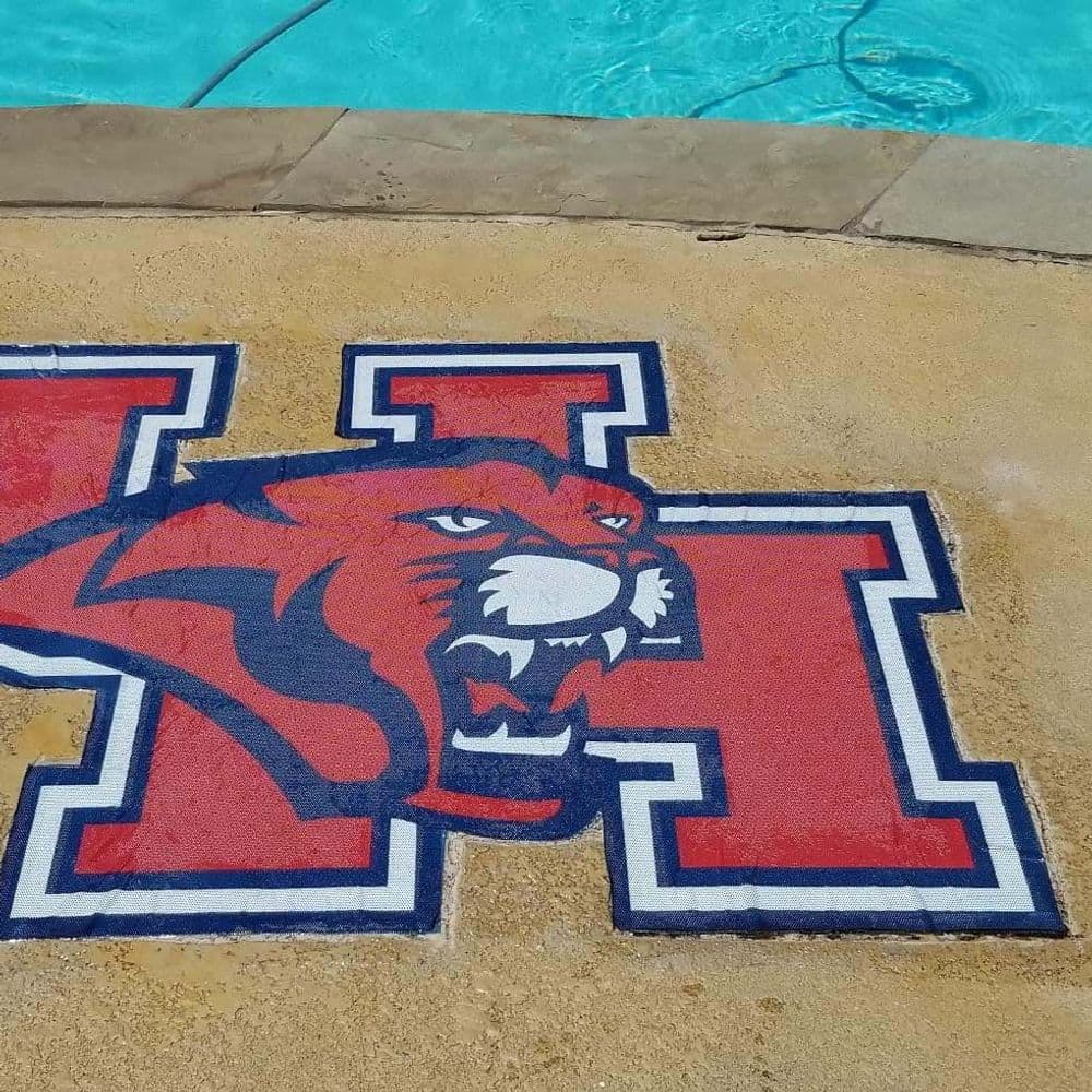 Painted logo of a fierce tiger with the letter "H" near a swimming pool.